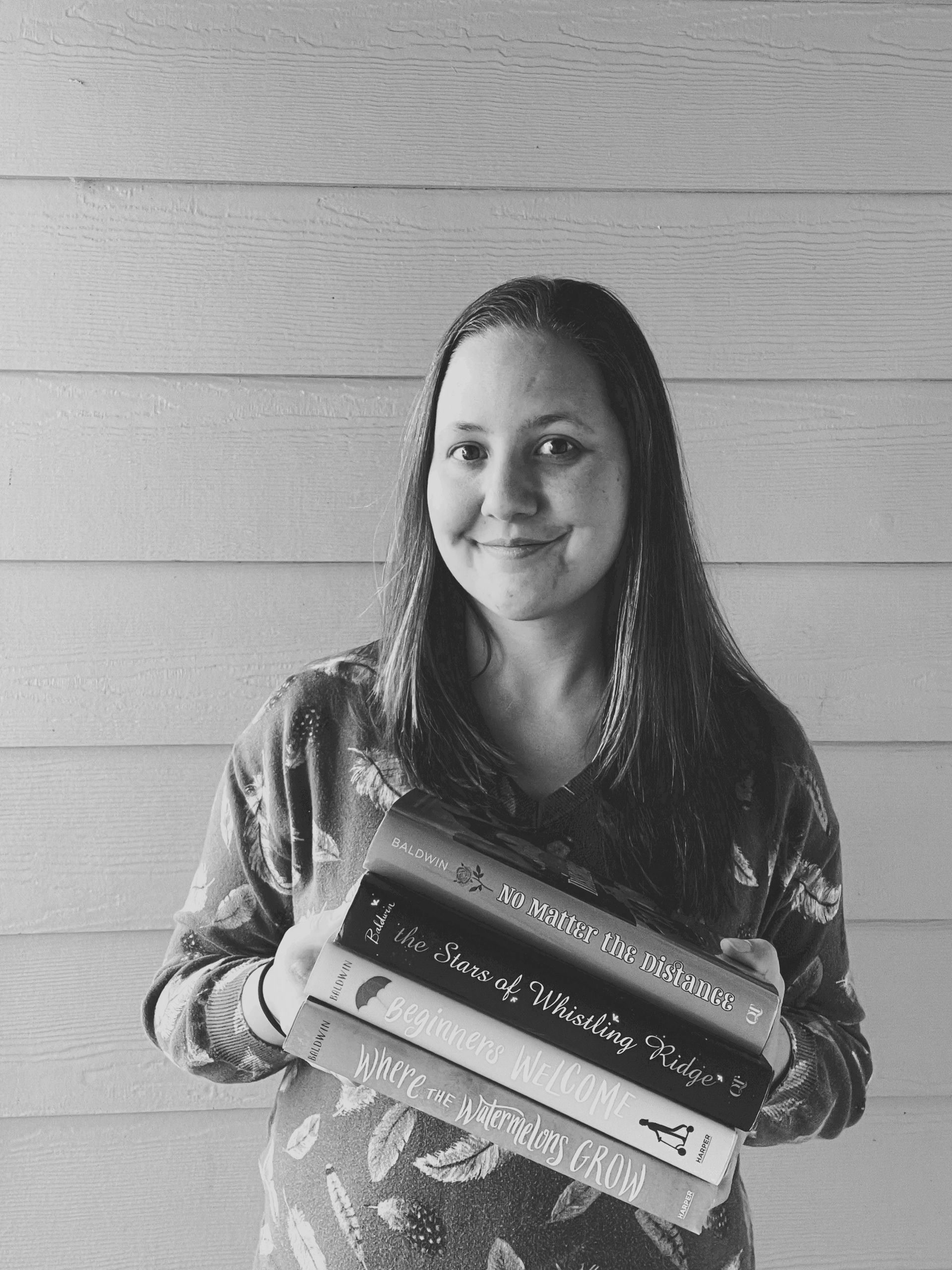 Cindy Baldwin smiling and holding a stack of her four published novels